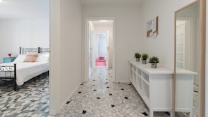 A hallway with a bed, a console table with potted plants, and a mirror. - Buonarroti (Florence)