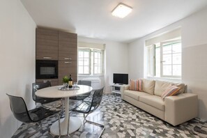 A modern living room with a round dining table, a sofa, and a TV. - Buonarroti (Florence)