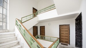 A multi-level interior with marble flooring, a green and wooden staircase, and a wooden door. - Buonarroti (Florence)