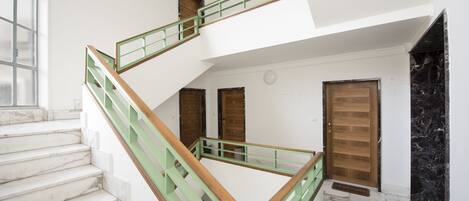 A multi-level interior with marble flooring, a green and wooden staircase, and a wooden door.