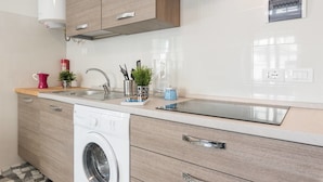 A modern kitchen with a built-in washing machine, stainless steel sink, and wooden cabinets. - Buonarroti (Florence)