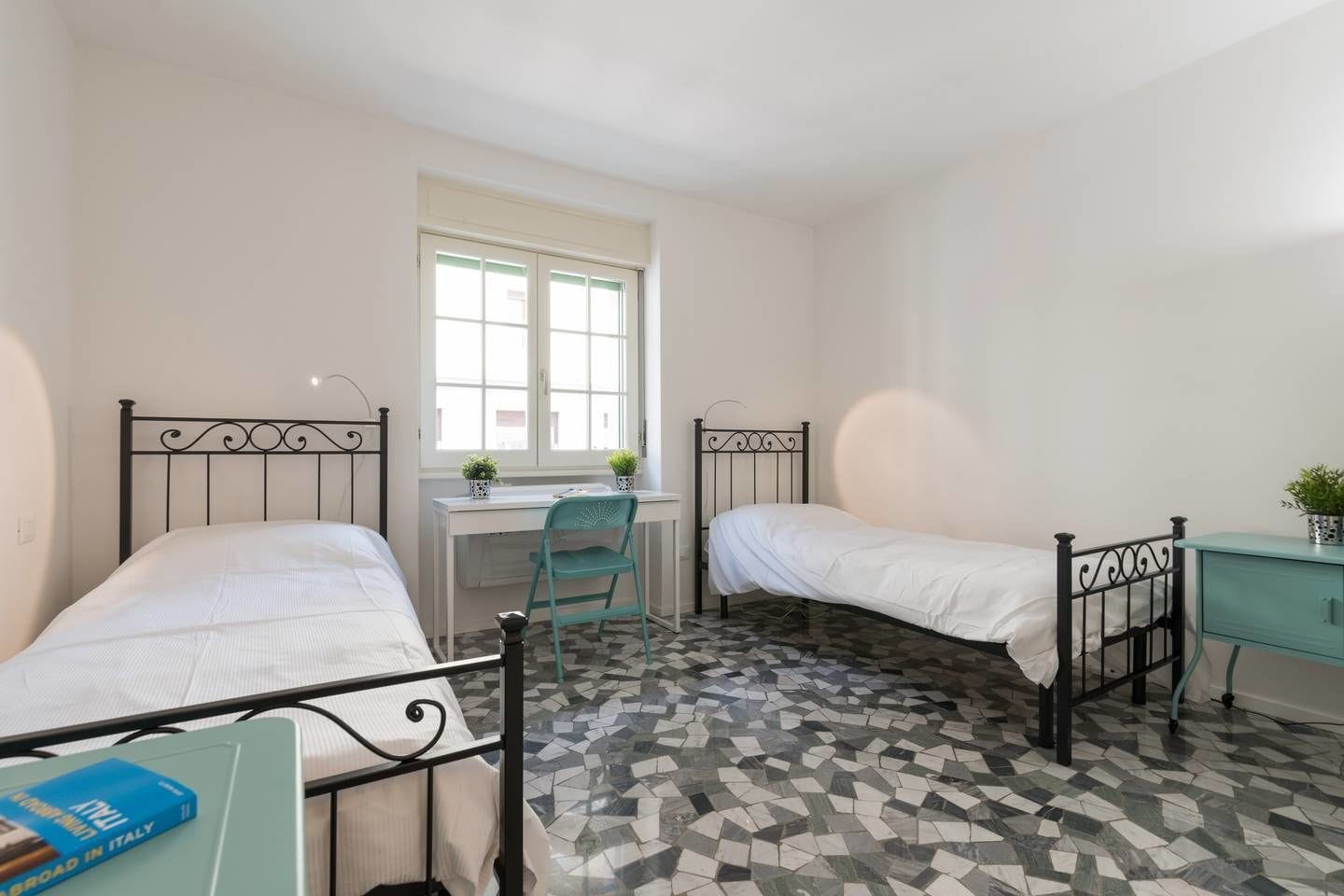 Ein Zimmer mit zwei Einzelbetten, einem Schreibtisch und einem Stuhl.
