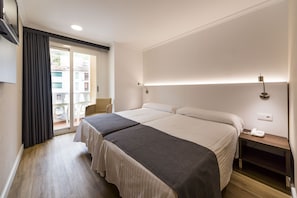 A hotel room with two beds, a small table, a chair, and a balcony with a view. - Rosaleda Del Mijares (Montanejos)