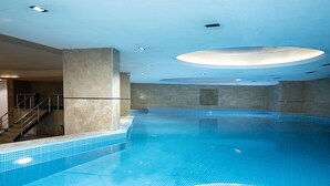 An indoor swimming pool with clear blue water, tiled walls, and a staircase leading to an upper level. - KONAK PARK HOTEL (Yomra)