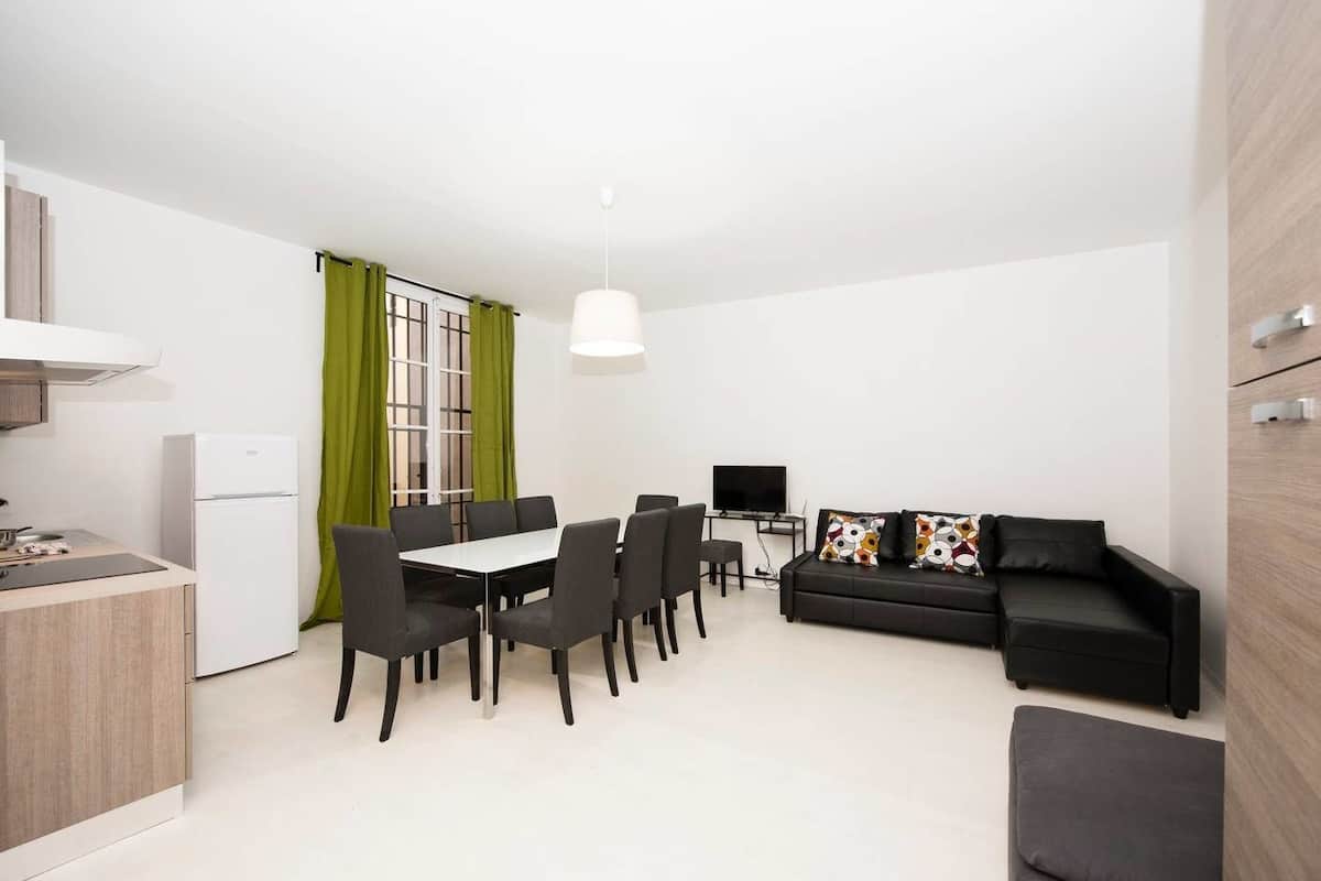 A modern, compact living space with a kitchenette, dining area, and seating area.