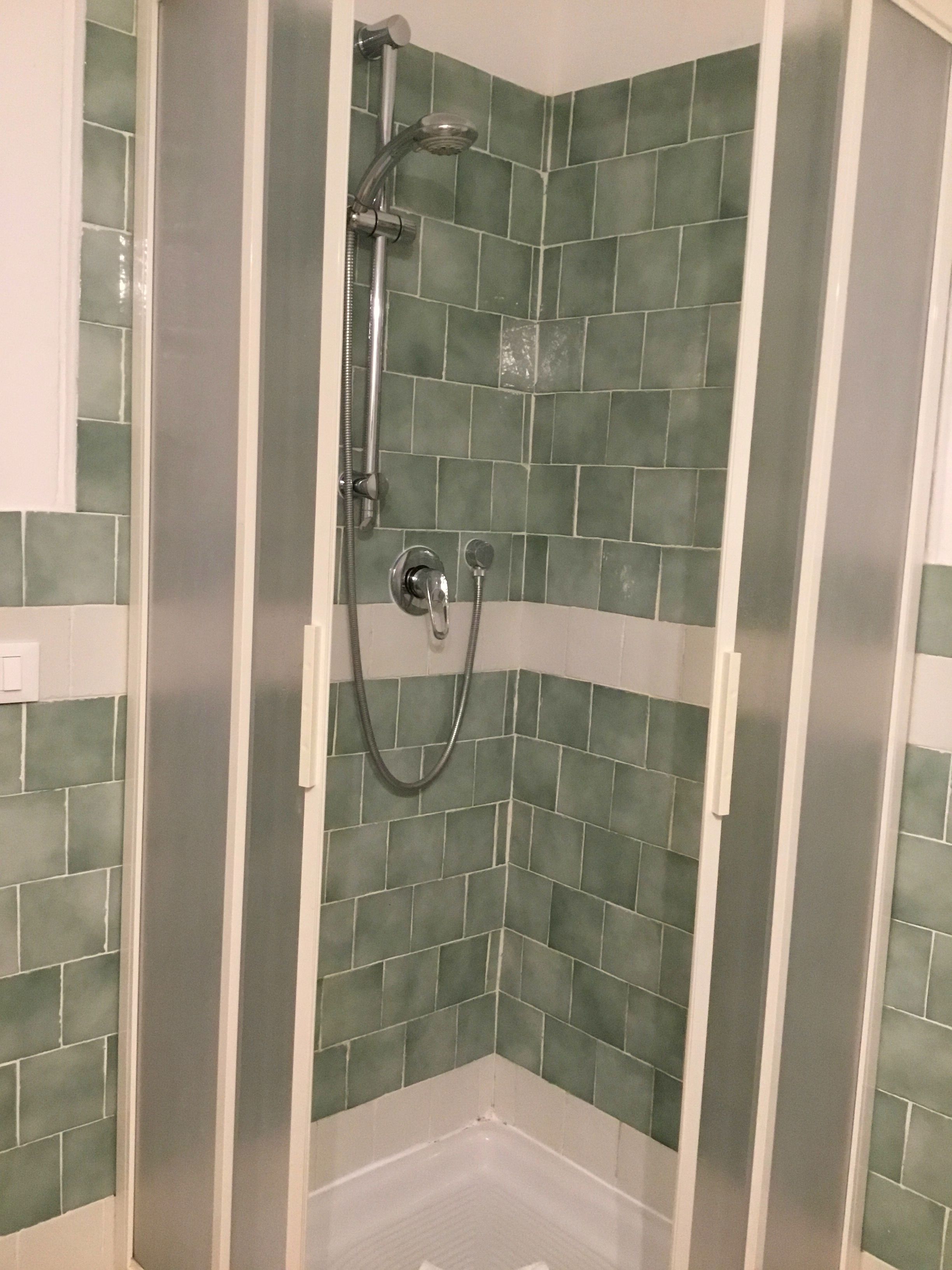 A shower with a handheld showerhead and a handheld shower attachment.