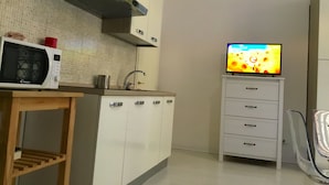 A kitchen with a microwave, a sink, cabinets, and a television. - Campidoglio (Florence)