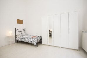 A bedroom with a bed, a nightstand, a wardrobe, and a radiator. - Campidoglio (Florence)