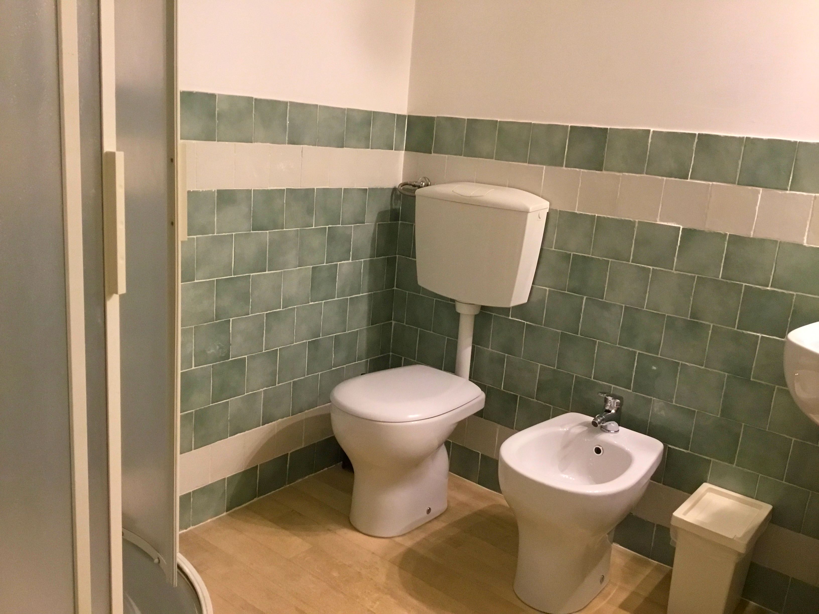 A bathroom with a toilet, bidet, and a trash bin.