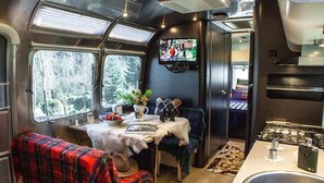 A cozy interior with a dining area, a TV mounted on the wall, and a kitchen with a sink.