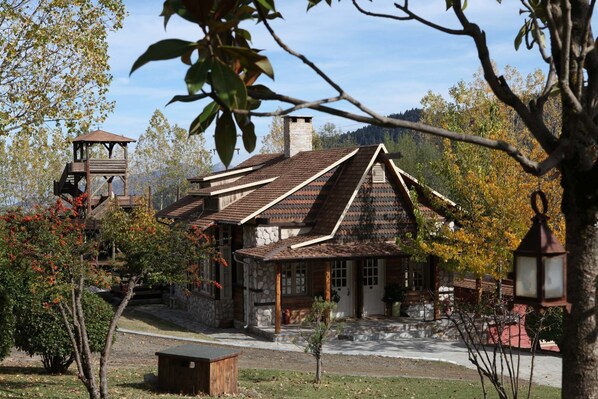 A rustic stone house with a sloped roof and a wooden tower.
