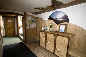 A reception area with a wooden reception desk, a mounted sign with a scenic view, and a wooden wall with various notices.