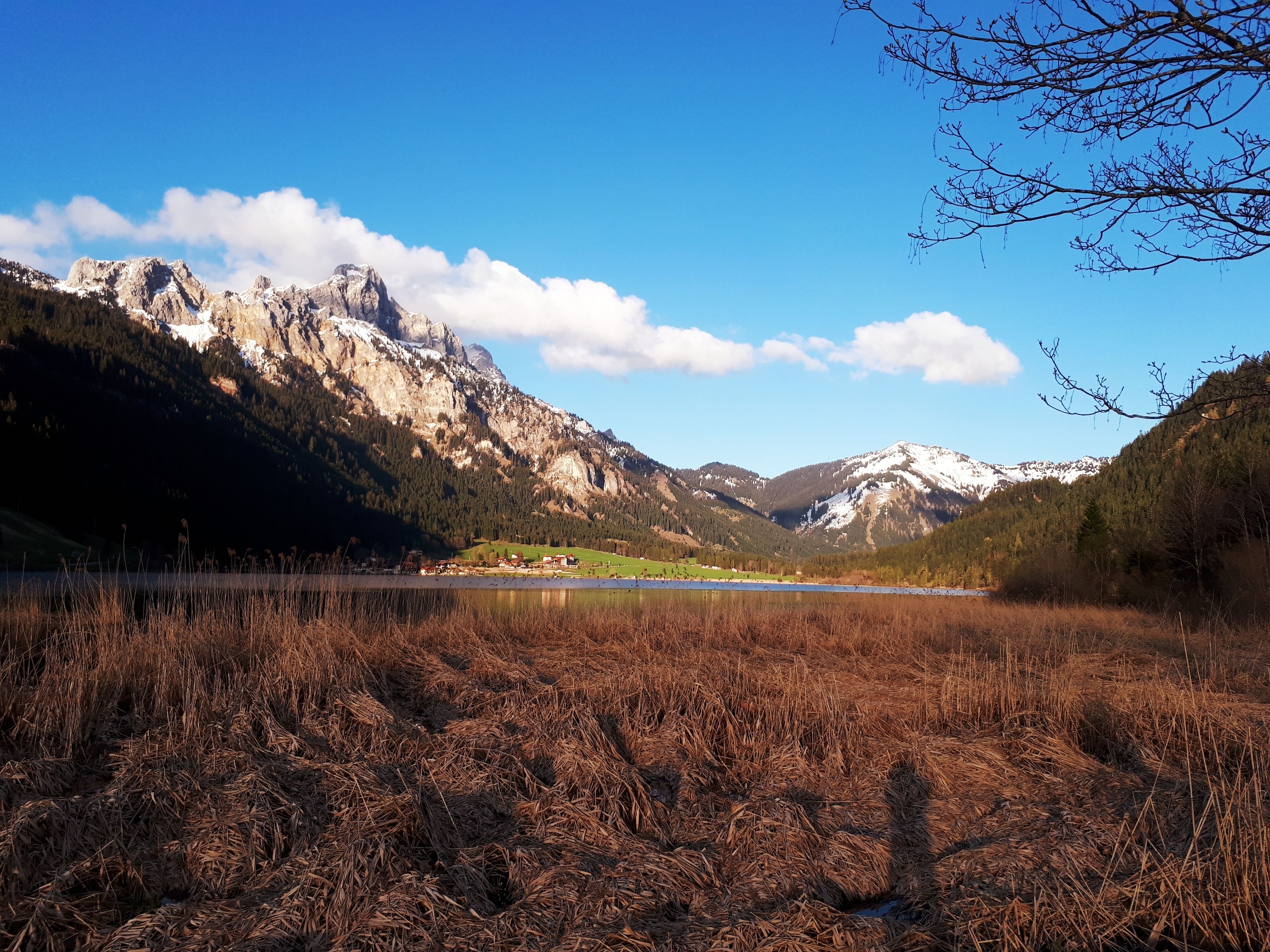A mountainous landscape with a lake, forested hills, and a clear sky.
