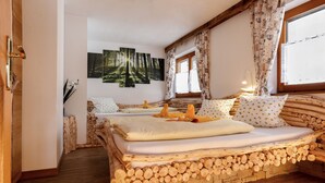 A cozy bedroom with a wooden log bed, a forest-themed wall art, and a window with curtains. - Wellness Appartementhaus Seebichl (Nesselwaengle)