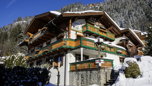 A traditional chalet with multiple balconies, wooden architecture, and a stone foundation. - Wellness Appartementhaus Seebichl (Nesselwaengle)