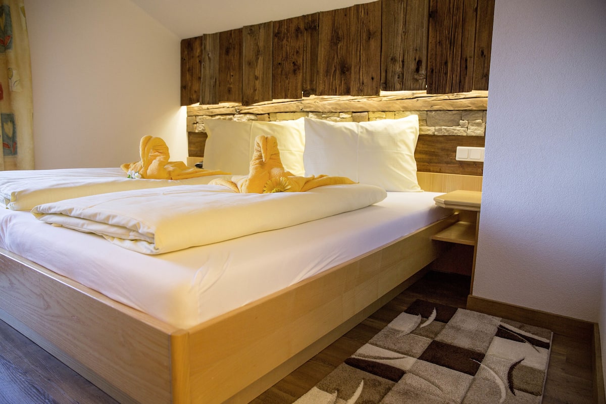 Una cama bien hecha con sábanas blancas y un cabecero de madera.