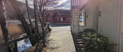 A paved pathway leading to a building with a red door and a white exterior.