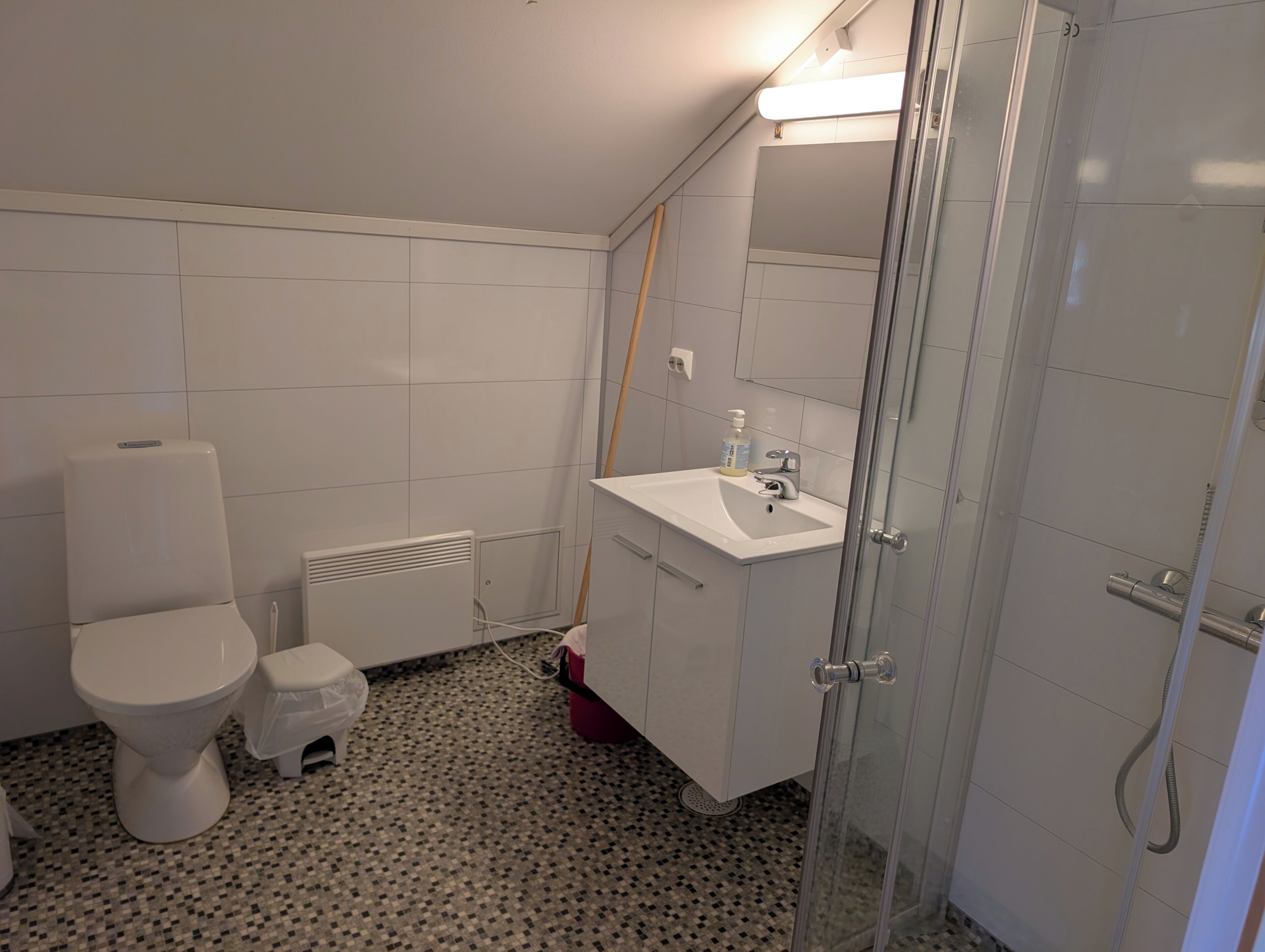 Een badkamer met toilet, wastafel, douche en betegelde wanden.