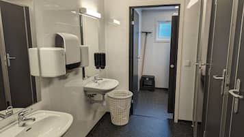 Un baño moderno con un lavabo blanco, un espejo y dispensadores de jabón para manos.