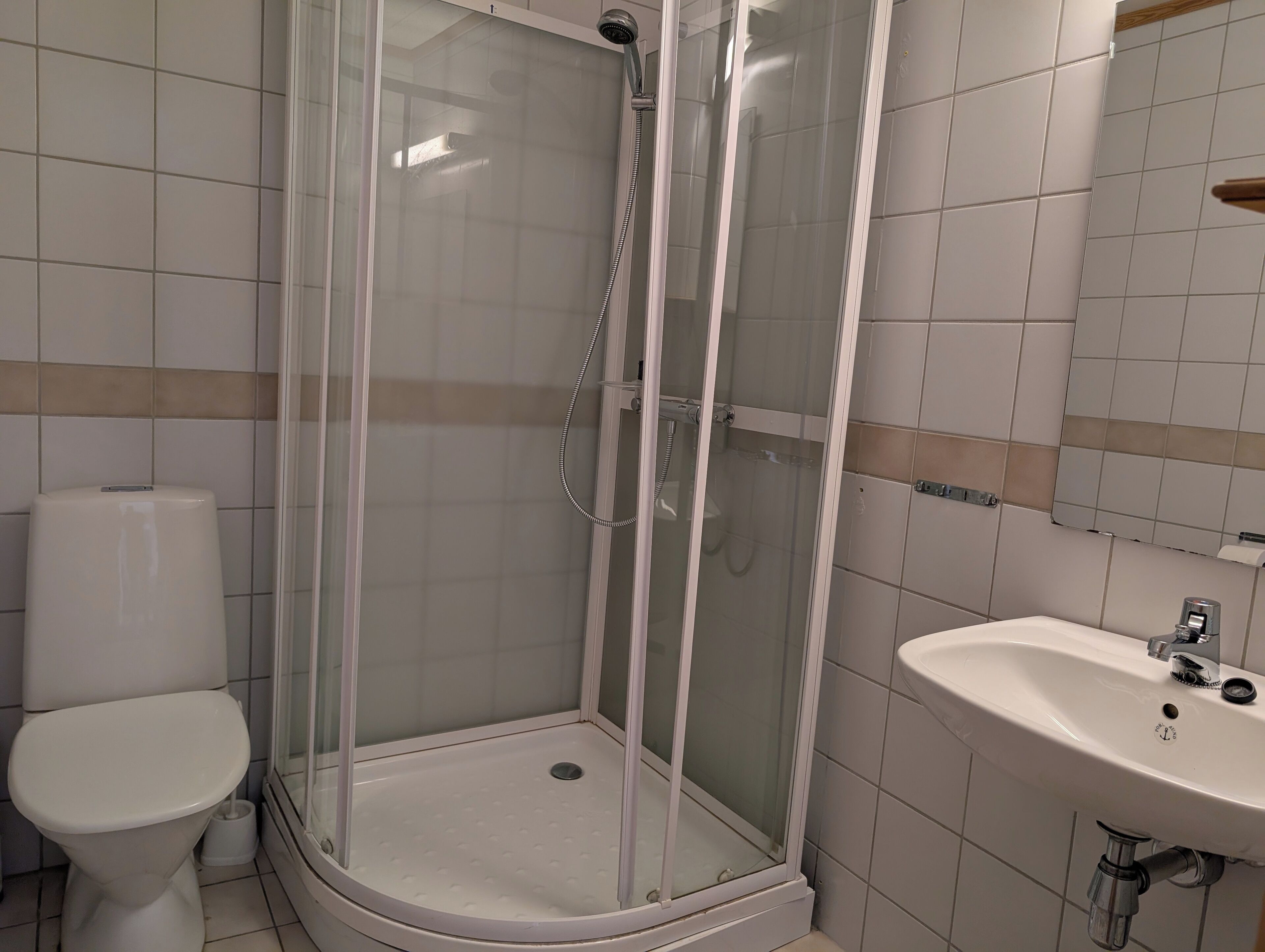 A bathroom with a glass-enclosed shower, a toilet, and a sink.