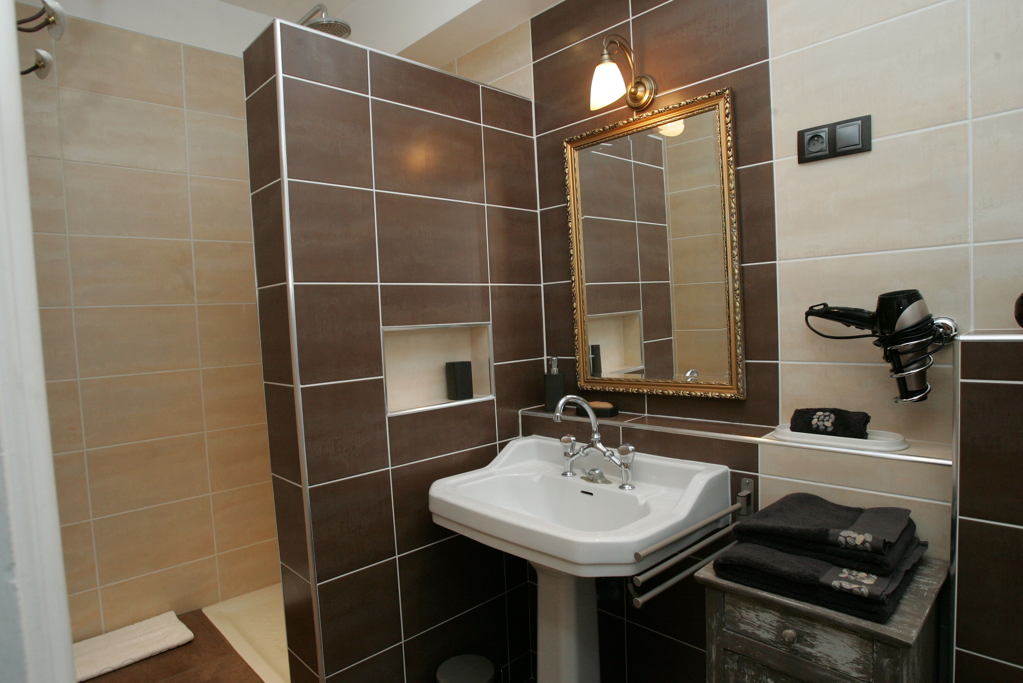 Une salle de bain avec un lavabo blanc, un miroir avec un cadre doré et un porte-serviettes.