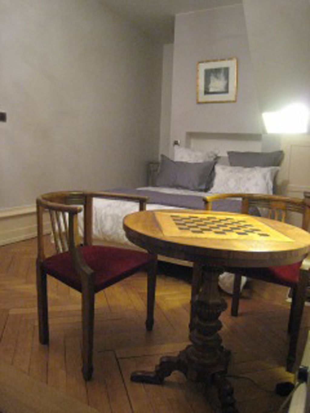 A room with a bed, a small table with a board game, and a chair.