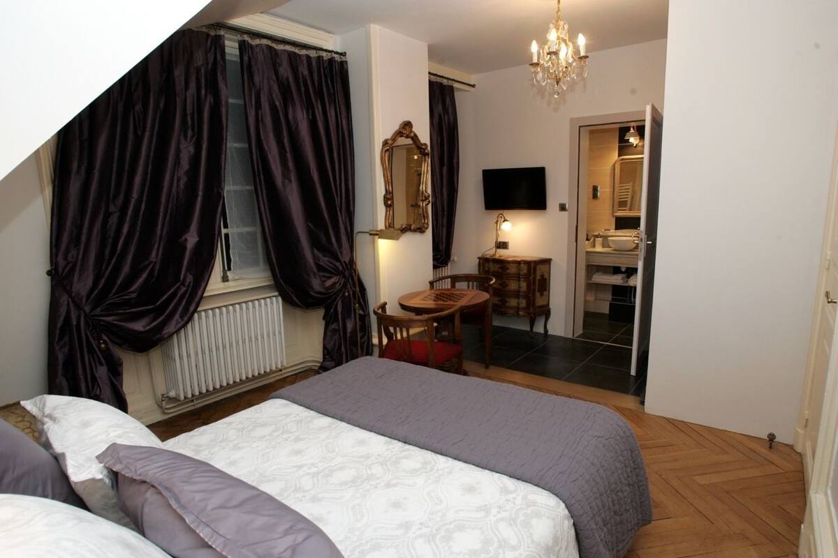 Une chambre à coucher avec un grand lit, une chaise, une petite table, un miroir et un téléviseur.
