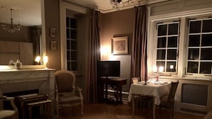 A dimly lit room with a fireplace, a television, and a dining table set for two.