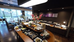 A buffet setup with various dishes and a floral centerpiece. - Hotel Route-Inn Grand Tokyo Asakusabashi (Tokyo)