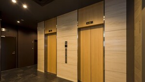 A modern elevator area with wooden paneling and floor tiles. - Hotel Route-Inn Grand Tokyo Asakusabashi (Tokyo)