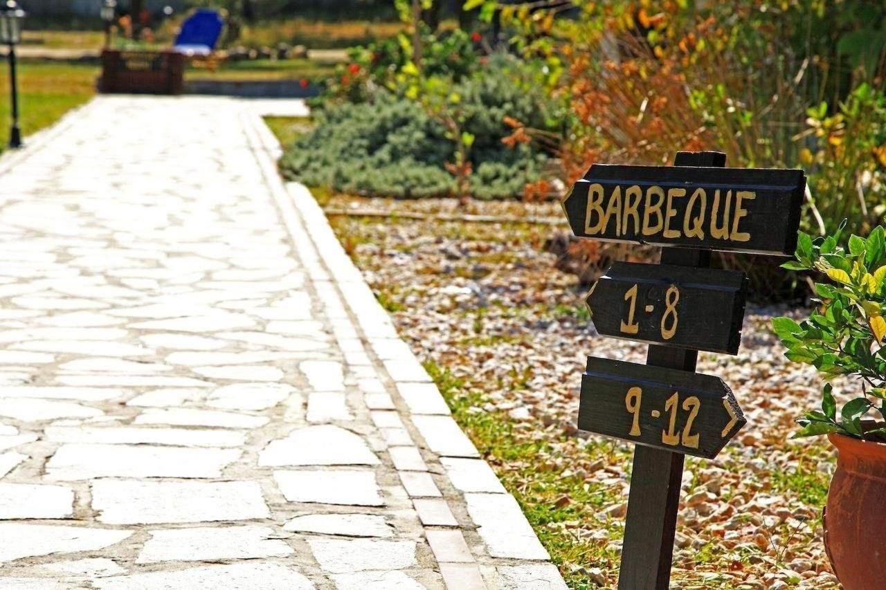 A stone pathway leading to a barbeque area with directional signs indicating time slots.