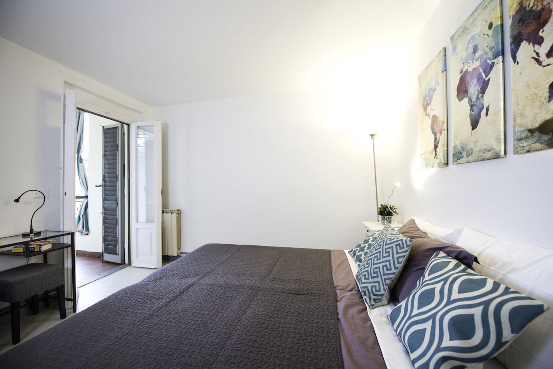 A bedroom with a bed, bedside table, lamp, and artwork on the wall.