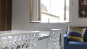A white table with chairs, a window, and a blue couch in the background.