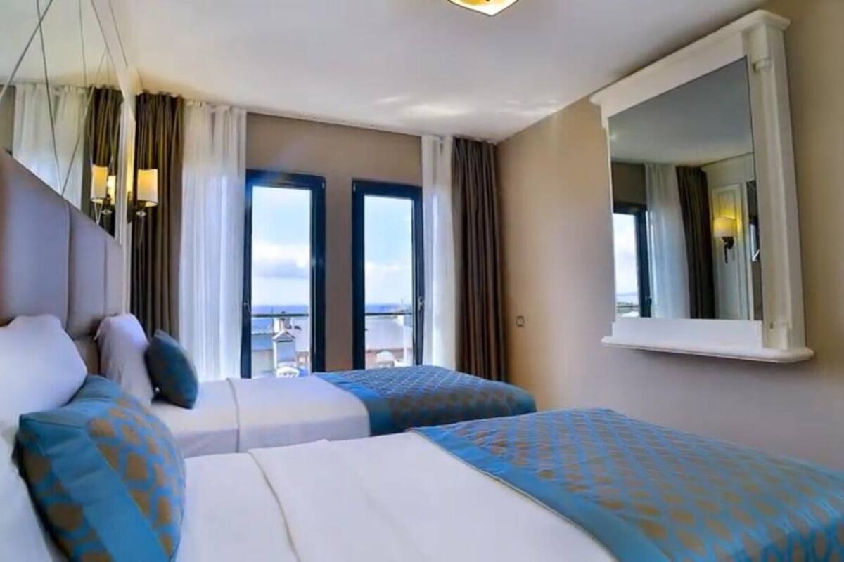 A hotel room with two beds, a large window, and a mirror.