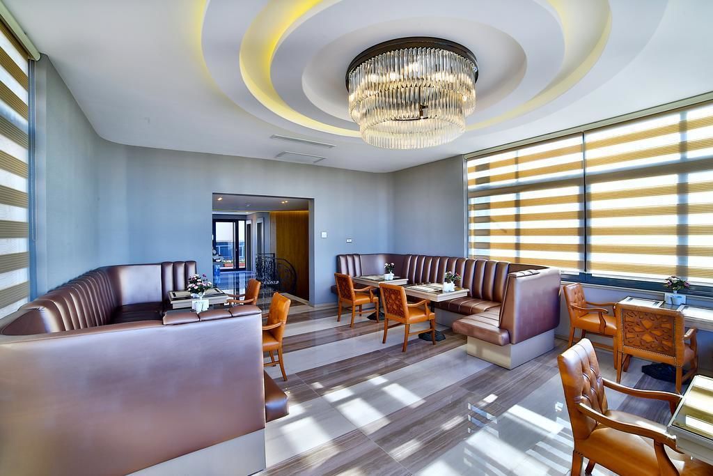 A modern dining area with a chandelier, leather booths, wooden tables, and chairs.