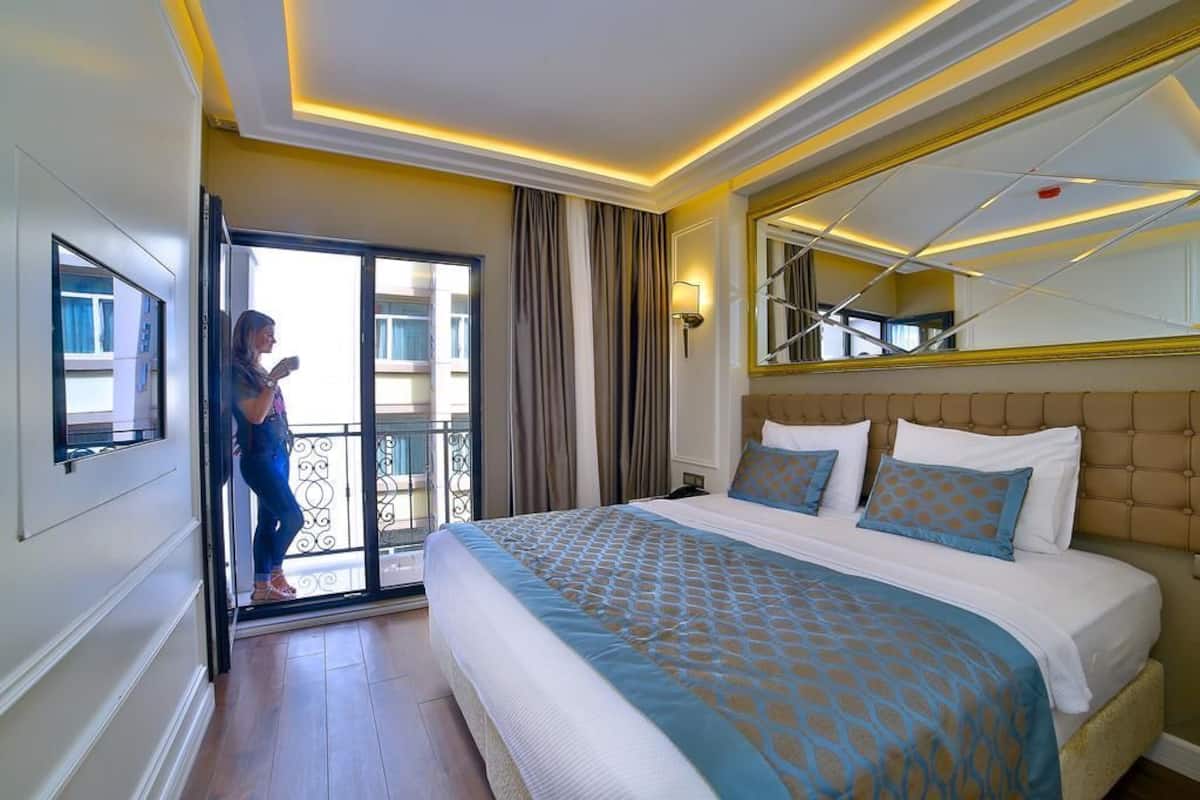 A hotel room with a large bed, a balcony with a view, and a modern ceiling design.