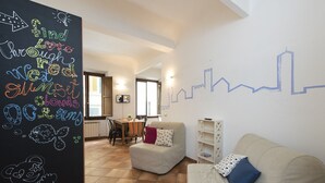 A cozy living room with a sofa, a dining area with a table and chairs, and a wall with a city skyline mural. - Faenza Double (Florence)