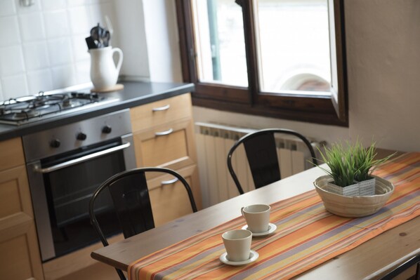 A kitchen with a stove, oven, and a dining table with two cups and a plant.