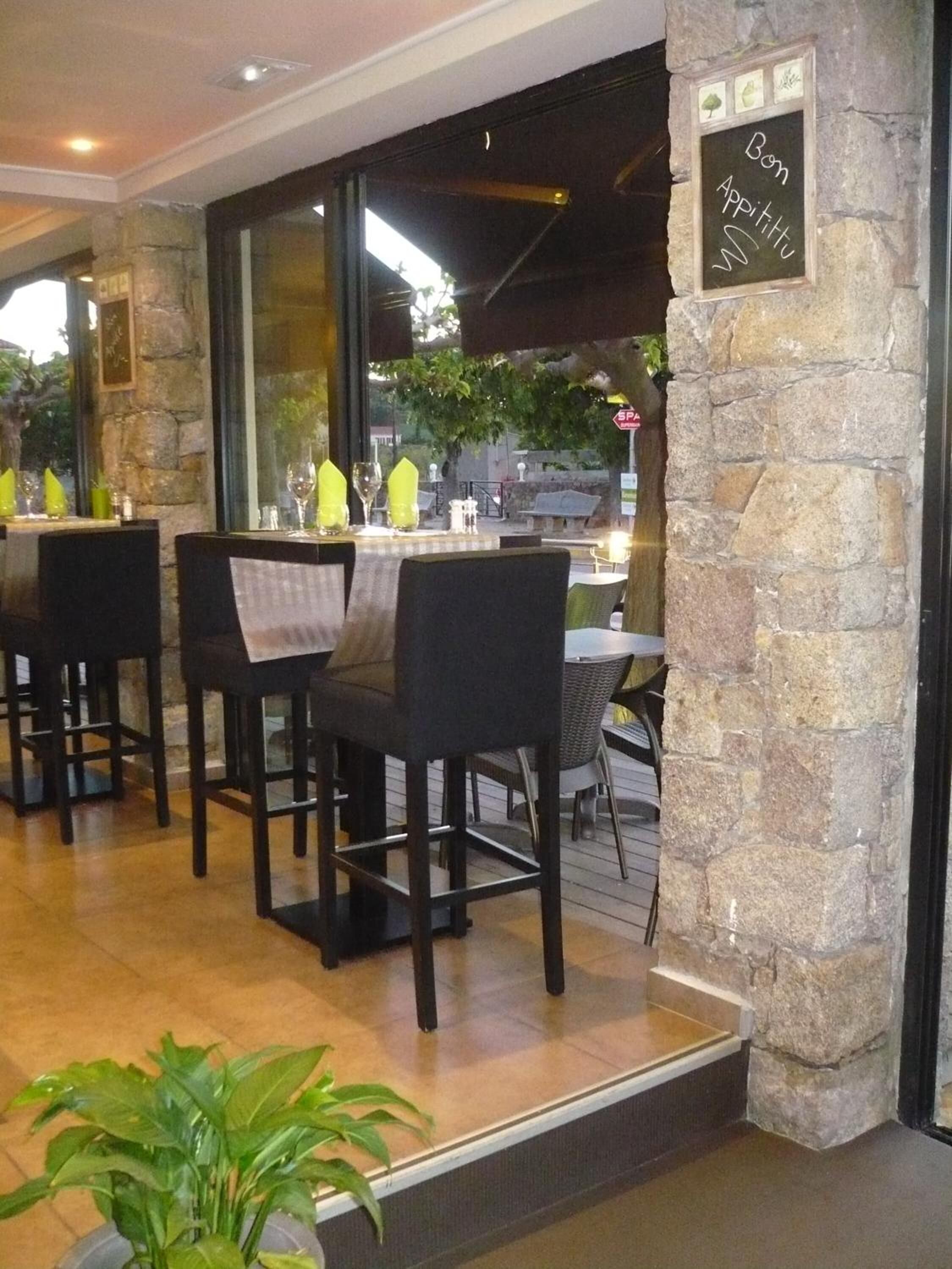 Un espace extérieur aménagé pour les repas, avec des murs en pierre, des tables et des chaises.