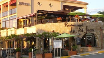 Un edificio de dos pisos con restaurante y bar en la planta baja y un hotel en el piso superior.