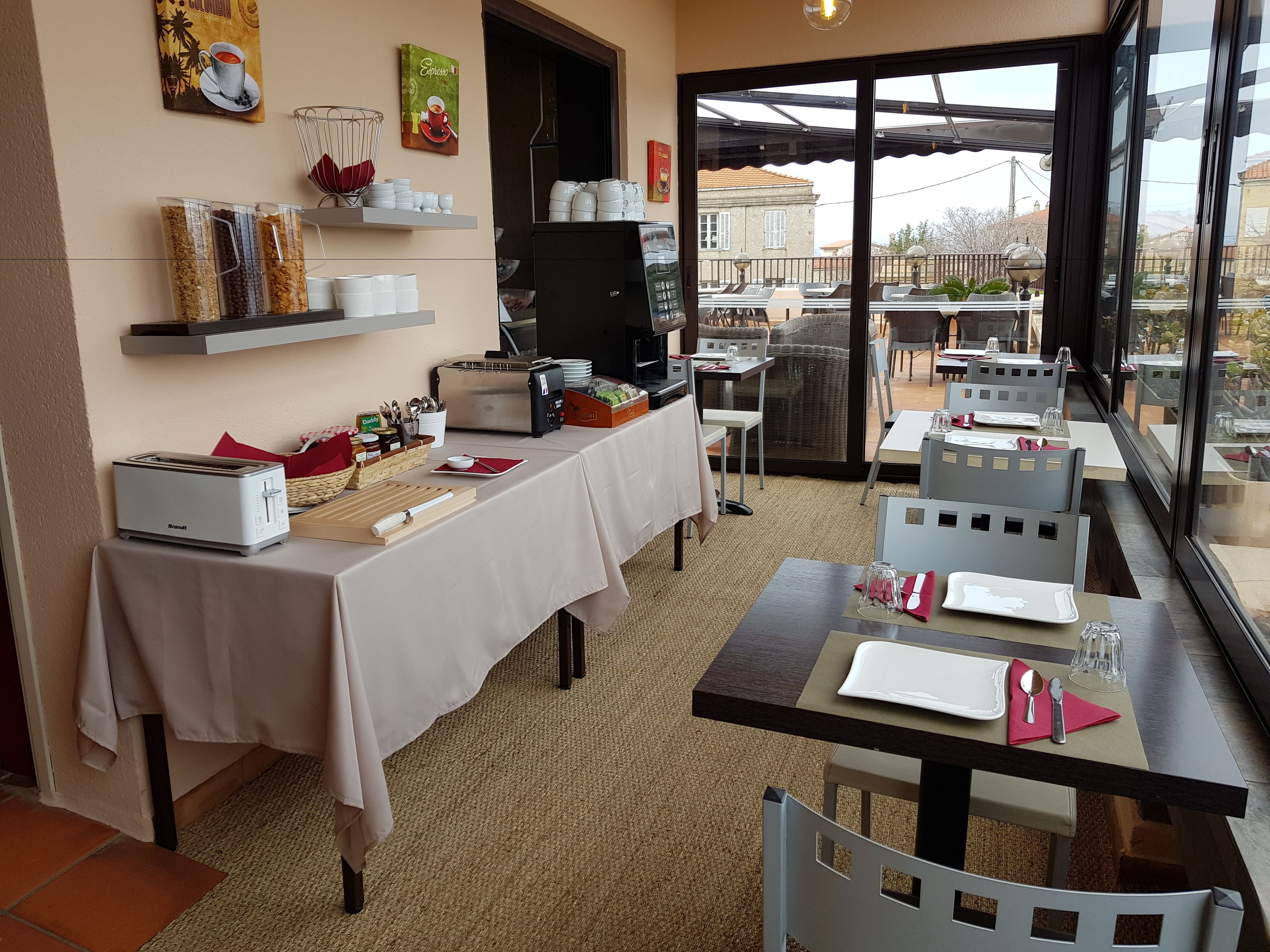 A dining area with tables set for service, a coffee machine, and a view of the outside.