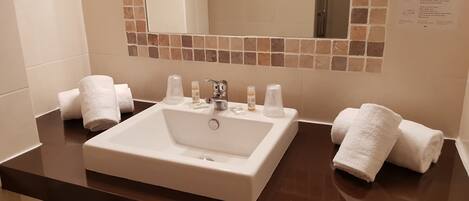 Une salle de bain avec un lavabo blanc, deux serviettes et des articles de toilette.