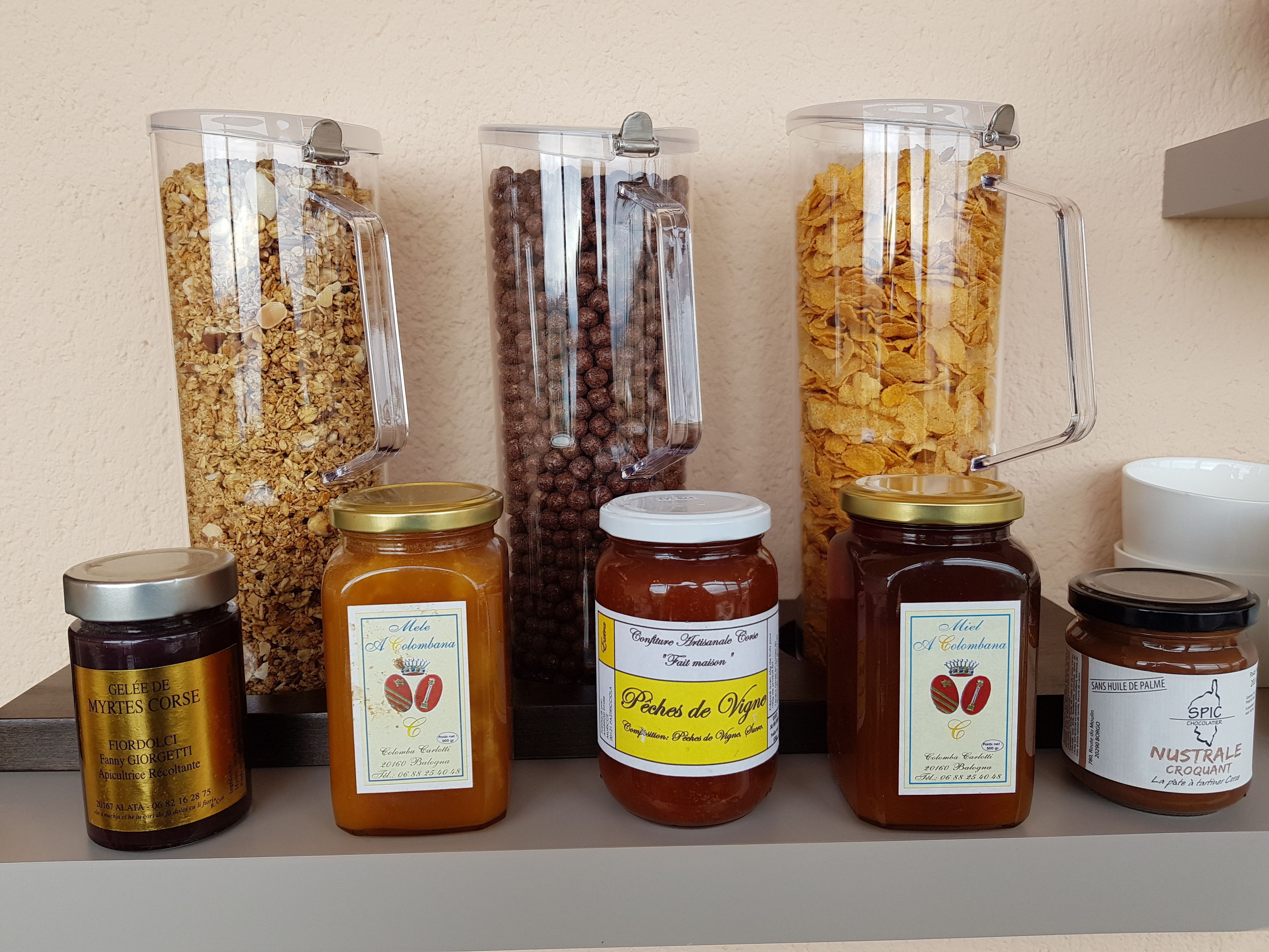 A shelf with various food items including jars of honey, jams, and snacks.