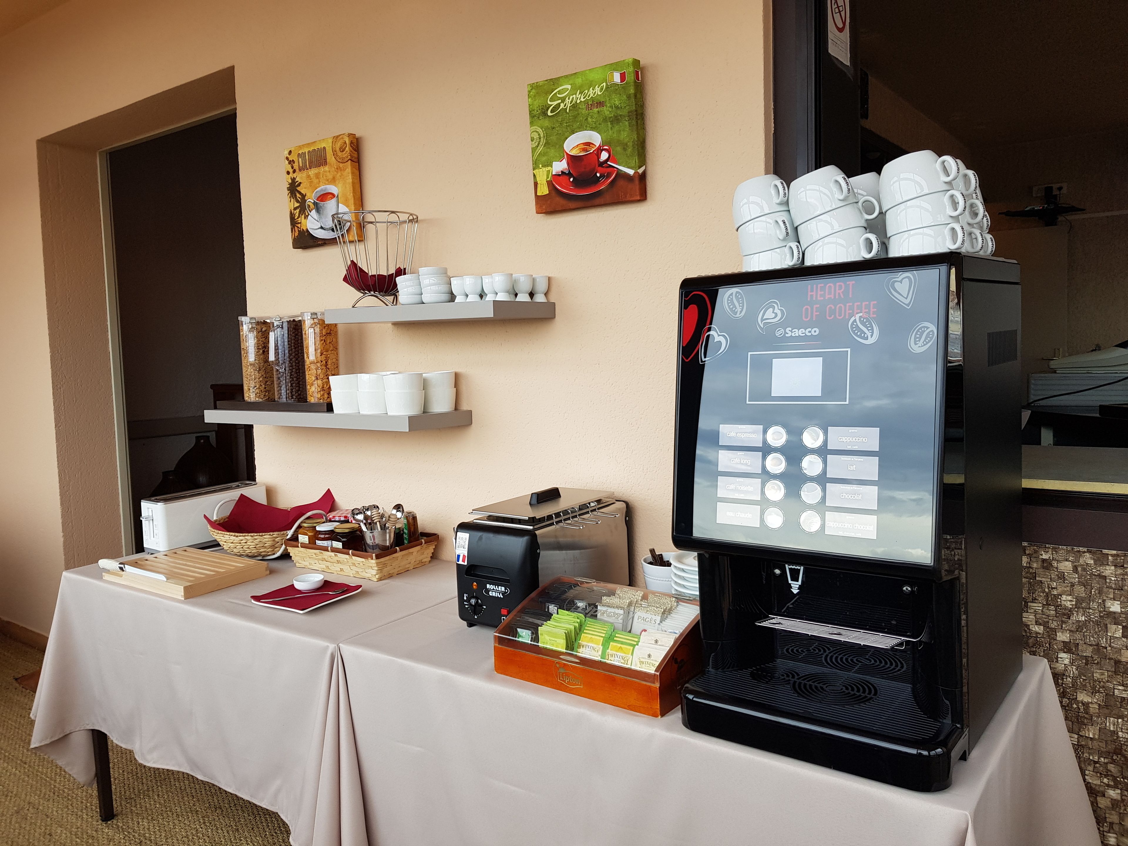 A coffee station with a coffee machine, cups, and a menu board.