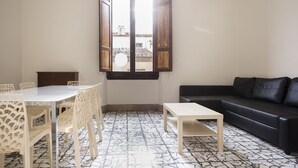 A living room with a dining area, a black sofa, and a large window with wooden shutters. - Fortezza Second floor (Florence)