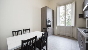 A compact kitchen with a dining table and chairs, a built-in oven, and a window providing natural light. - Fortezza Second floor (Florence)