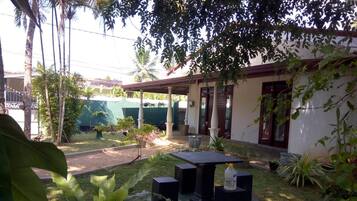 A courtyard with a table and chairs, surrounded by potted plants and a building with a covered entrance.
