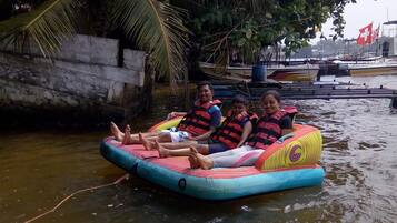 A group of people on a colorful inflatable raft in a body of water, with boats and a Swiss flag in the background.