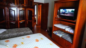 A bedroom with a bed, a television on a wooden stand, and a wardrobe. - Residencial Encantos de Gramado (Gramado)