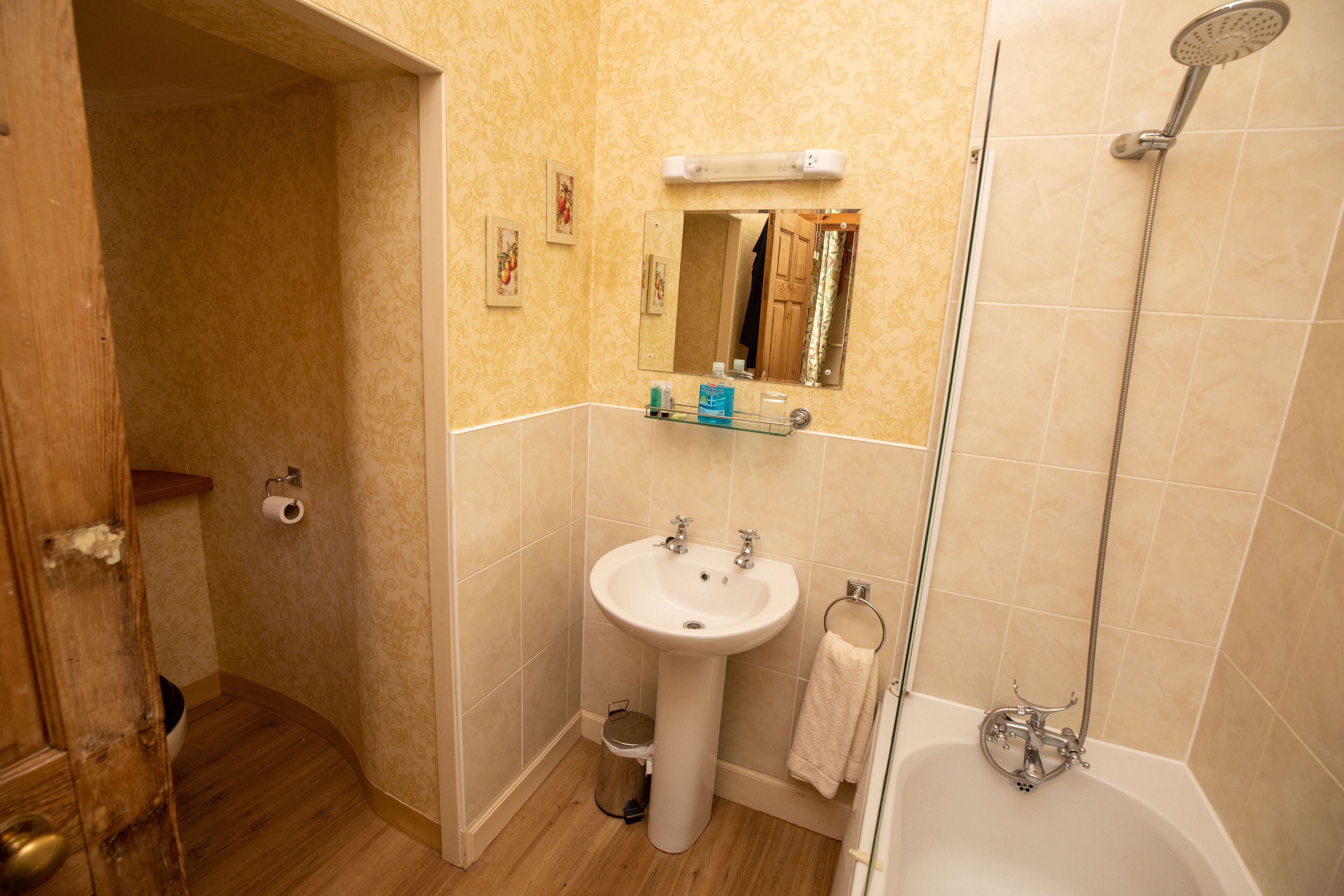 A bathroom with a sink, mirror, toilet, and shower.